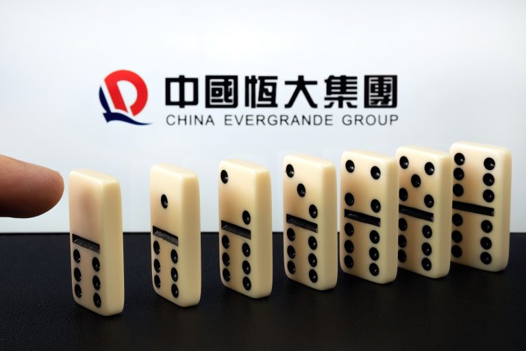 Finger,Touching,Domino,Blocks,And,Blurred,China,Evergrande,Group,Logo.