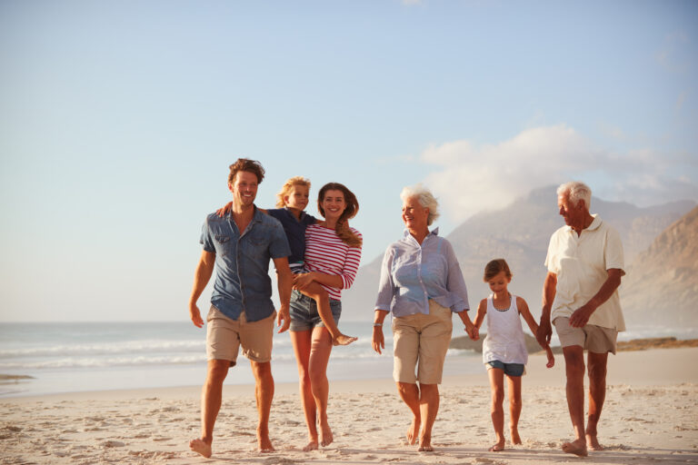 Multi,Generation,Family,On,Vacation,Walking,Along,Beach,Together