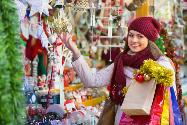 Happy,Young,Woman,Choosing,Christmas,Decoration,At,Market